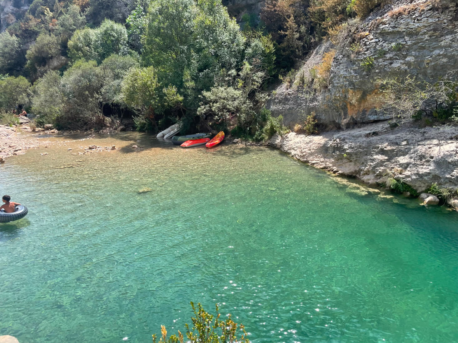 Turquoise river pool with kayaks resting on the bank